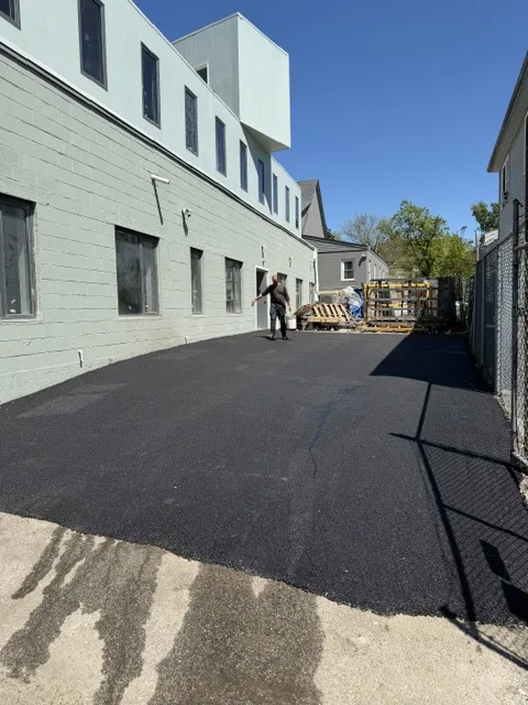 Freshly paved asphalt lot alongside a commercial building