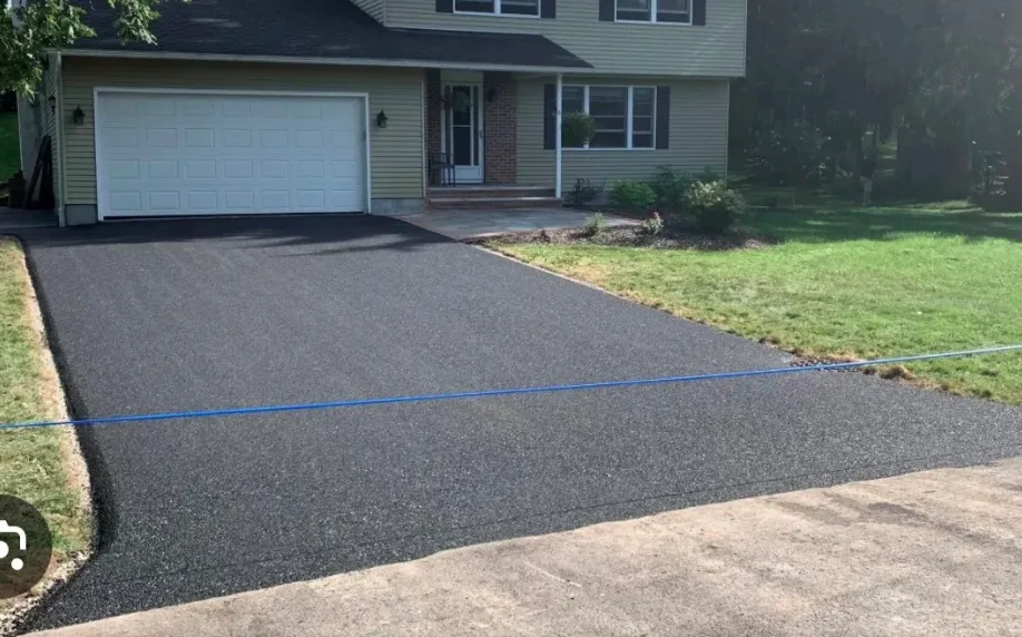 Completed asphalt driveway with crisp edges in front of a colonial home