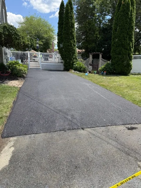 Fresh asphalt parking area beside a backyard pool deck