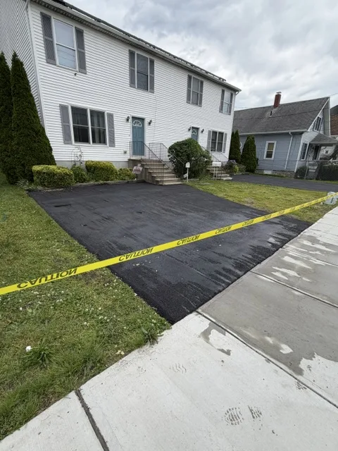 New townhouse driveway marked with caution tape while the asphalt cures